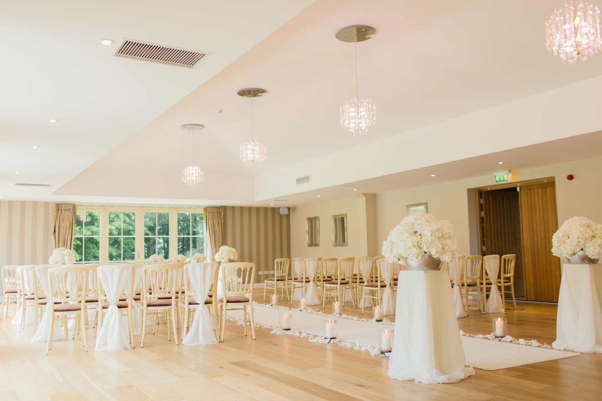 A bright venue ceremony room set with chandeliers.