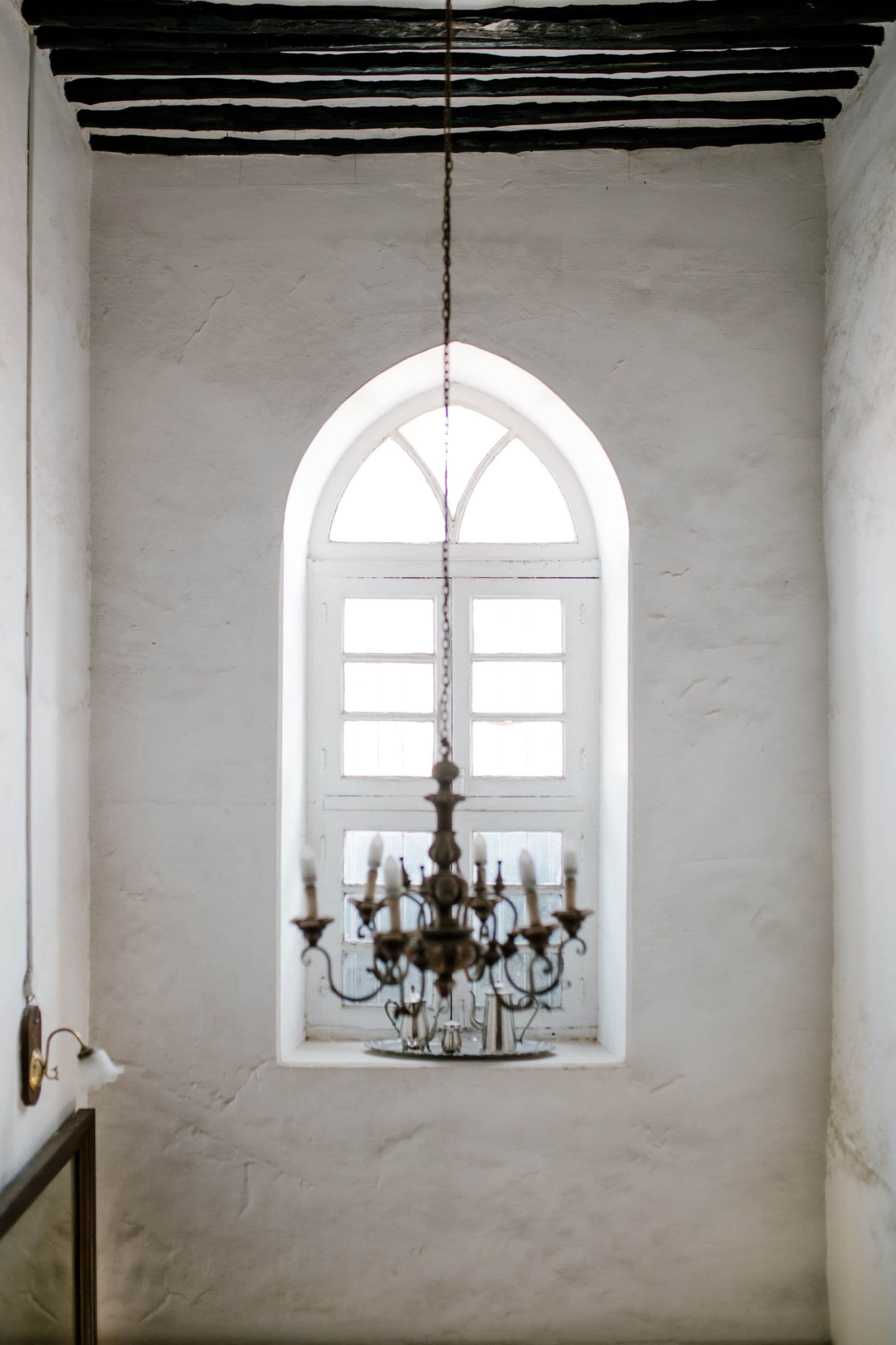A chandelier in front of an arched window at a venue.